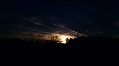 Silhouette of electricity pylon against sky at night