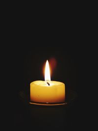 Close-up of illuminated candle against black background