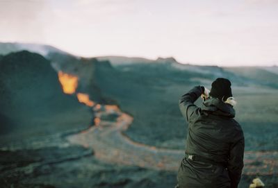 Rear view of couple standing on mountain against sky