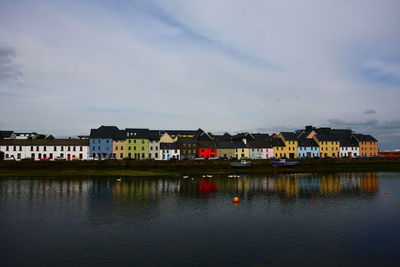 Houses by lake in town against sky