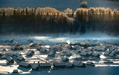 Snow covered houses and trees on landscape during winter