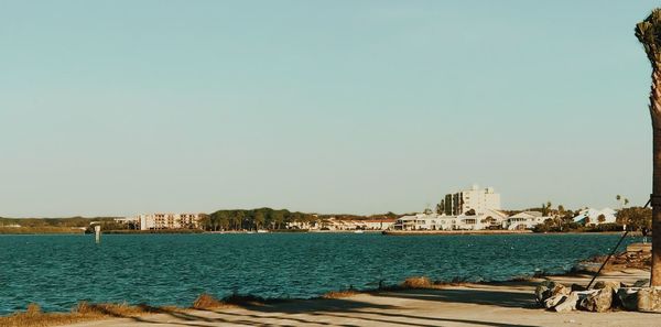 Sea by buildings against clear sky