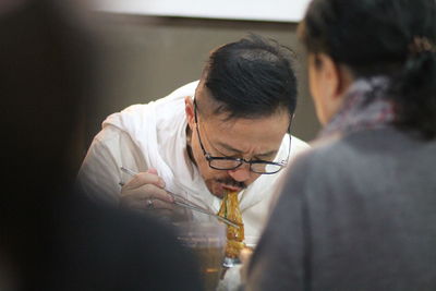 A man eating noodle in a restaurant 