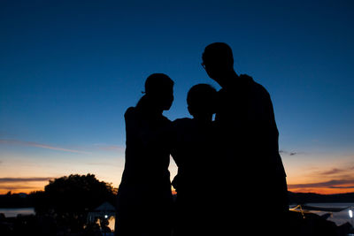 Silhouette family standing against sky during sunset