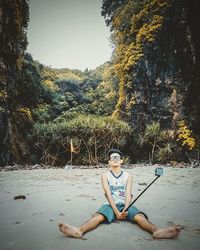 Portrait of young woman sitting on land against trees