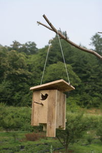 Close-up of birdhouse on wooden post in field against sky