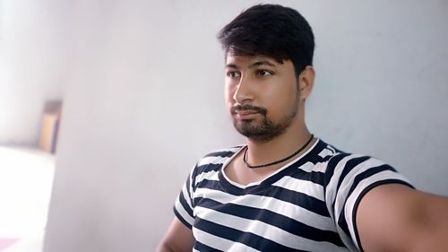 Portrait of young man standing against wall