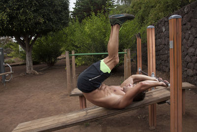 Rear view of woman sitting on tree