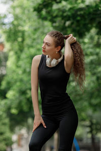 Young woman holding hair looking away at park