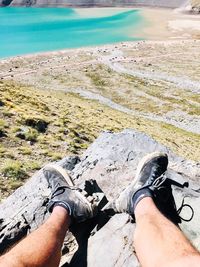 Low section of man relaxing on rock at beach