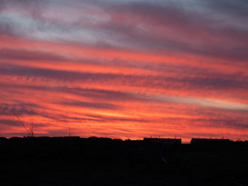 Silhouette landscape against dramatic sky during sunset