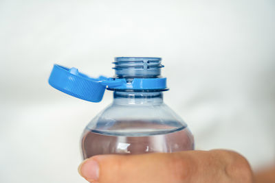 Cropped hand holding bottle against white background