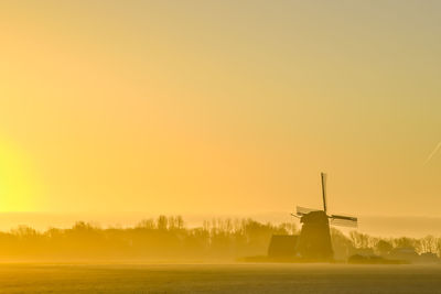 'breezand, the netherlands. march 2022. sunrise in the polder with mill in background.