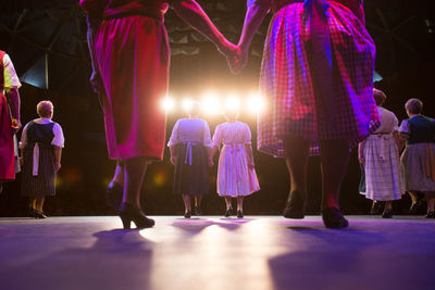 Rear view of women holding hands while standing on stage