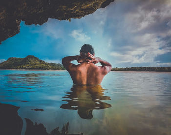 Full length of shirtless man in sea against sky