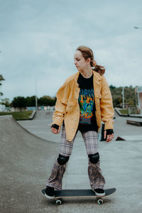 Young woman skateboarding on road in city