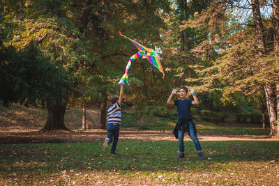 Happy siblings playing kites in park