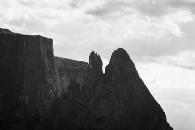 Low angle view of rocky mountains against sky in black and white 