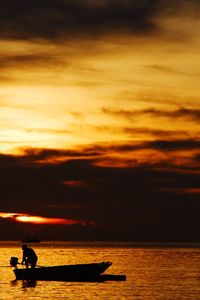 Silhouette person in sea against sky during sunset