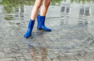 Low section of girl standing on puddle