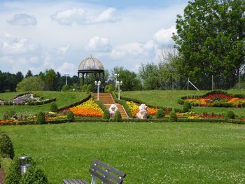 Scenic view of garden in park against cloudy sky
