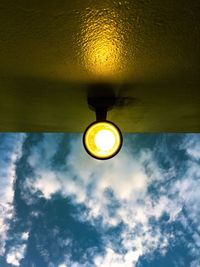 Low angle view of illuminated light bulb against sky