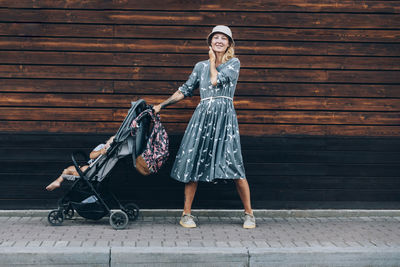 Woman with baby stroller standing on footpath