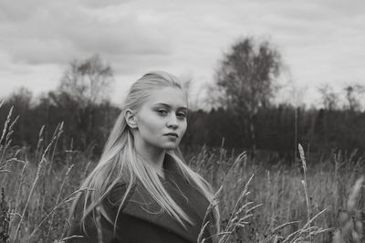 Portrait of young woman on field against sky