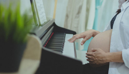 Midsection of woman playing piano at home
