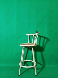 Empty chair on table against green wall