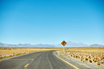 View of road sign against clear blue sky