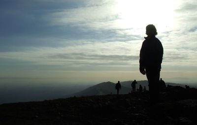 Silhouette men on landscape against sky