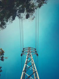 Low angle view of electricity pylon against blue sky