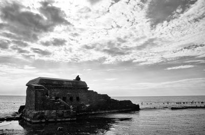 Built structure in sea against cloudy sky