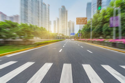 Road leading towards city buildings against sky