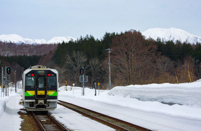 Train on railroad track by snowcapped mountain against sky