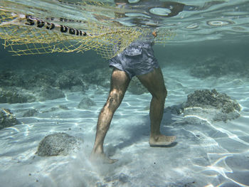 Low section of man with fishing net undersea