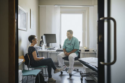 Male physician discussing with senior woman in clinic