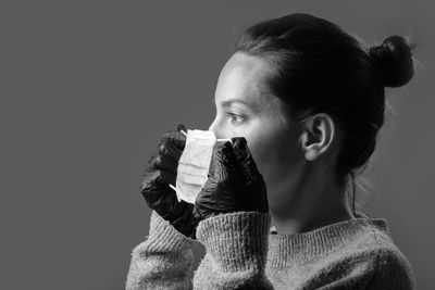 Portrait of young woman drinking glasses against black background