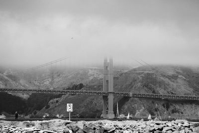Suspension bridge over mountain against sky