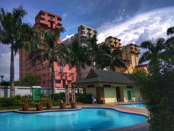 Palm trees by swimming pool against sky