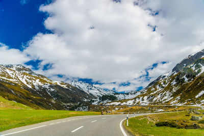 Road leading towards mountains against sky