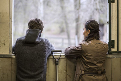 Rear view of young couple looking through window of horse stable