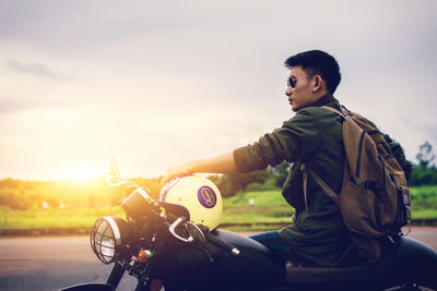 Man sitting on motorcycle against sky