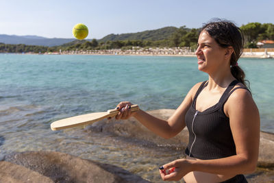 Teenager girl is playing in tennis and having fun on beautiful beach. summer activities concept