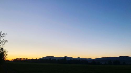 Scenic view of silhouette field against clear sky during sunset