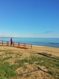 Man standing on beach against clear blue sky