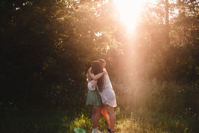 Happy girlfriends embracing in forest during summer