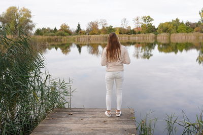 Rear view of woman standing by lake