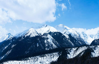 Low angle view of snowcapped mountains against blue sky